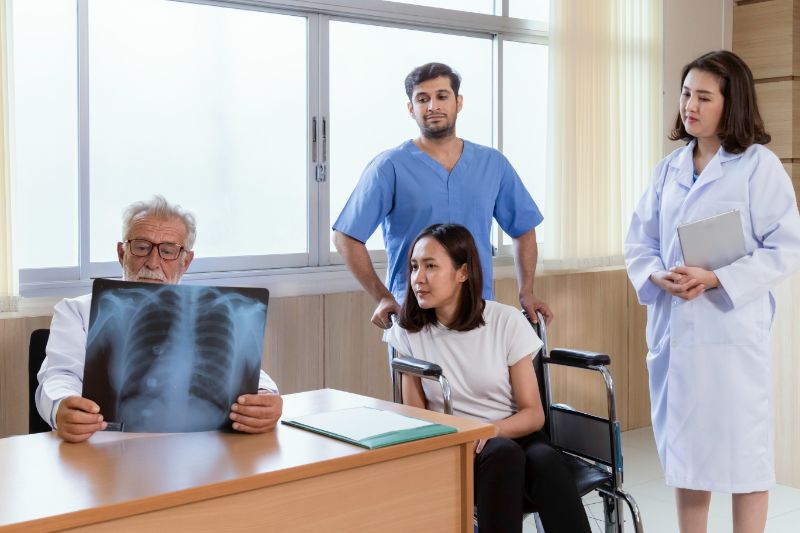 Doctors looking at an xray film with the patient and nurse